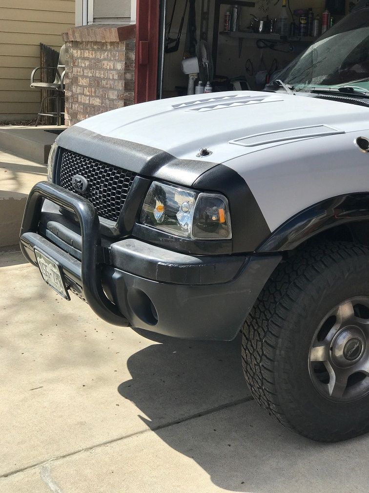 Front of a white Ford Ranger with a black bull bar and bug deflector