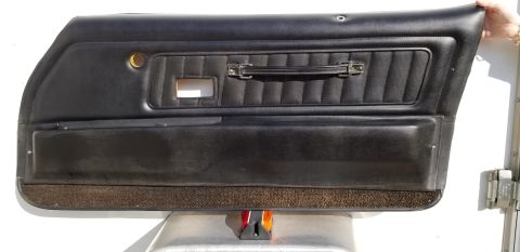 1973 Chevrolet Camaro - A black car door panel with a textured insert and a chrome pull handle is displayed.