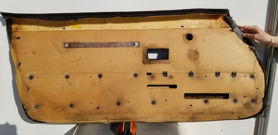 Car door panel with yellowing insulation and various screw holes