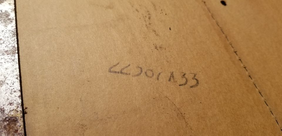 Handwritten numbers "66001A33" on a brown surface, possibly cardboard