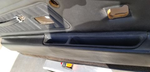 1973 Chevrolet Camaro - Close-up of a car's interior door panel, showing wear and tear on the fabric and plastic components.
