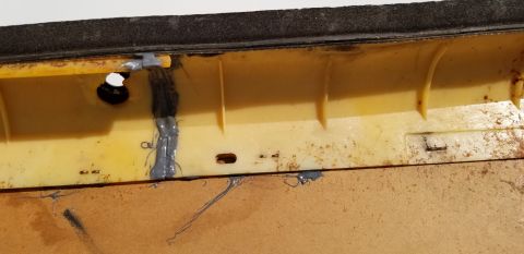 1973 Chevrolet Camaro - Close-up of a damaged yellow plastic car interior component with visible sealant repairs.