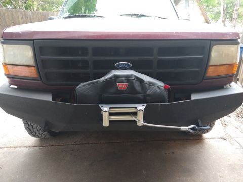 1996 Ford Bronco - Front view of a maroon Ford Bronco with an aftermarket bumper and winch.
