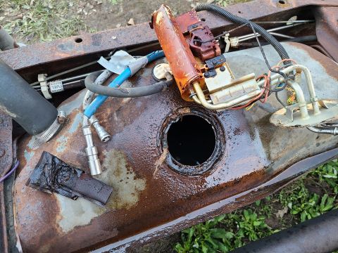 1995 Ford F-150 - Fuel tank and pump assembly removed from a vehicle. Visible rust and wear on the tank.