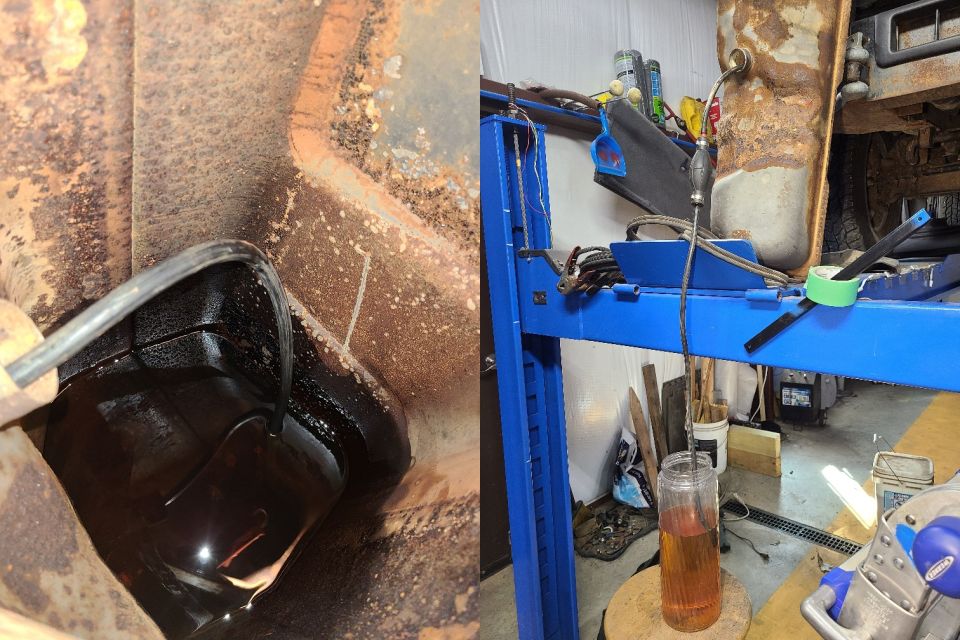 Undercarriage of a rusty vehicle with a black oil filter, and a blue vehicle lift in a workshop