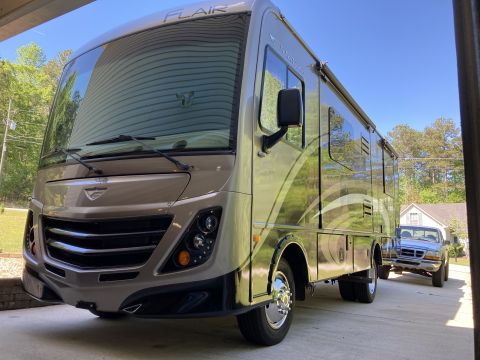 2015 Ford F-550 - A Fleetwood Flair motorhome is parked in a driveway, with a pickup truck visible behind it.