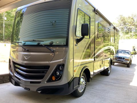 2015 Ford F-550 - A tan Fleetwood RV is parked in front of a Ford Ranger pickup truck.