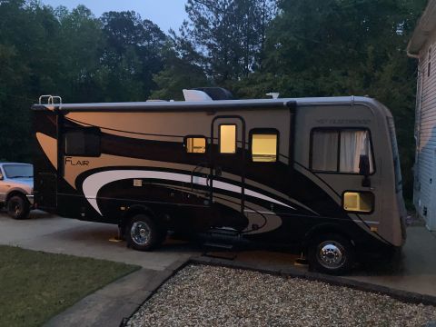 2015 Ford F-550 - A motorhome with a distinctive graphic design is parked next to a pickup truck.