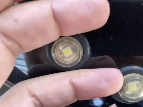 2015 Ford F-550 - A close-up view shows a round LED marker light, partially covered by a finger. Text from Supermotors.net is visible at the bottom.
