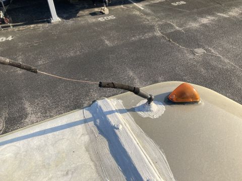 2015 Ford F-550 - Close-up of an RV roof showing an antenna mount and an orange marker light with sealant around the base.