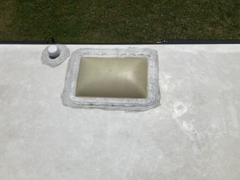 2015 Ford F-550 - Close-up view of a roof vent and a plumbing fixture on the white roof of an RV.