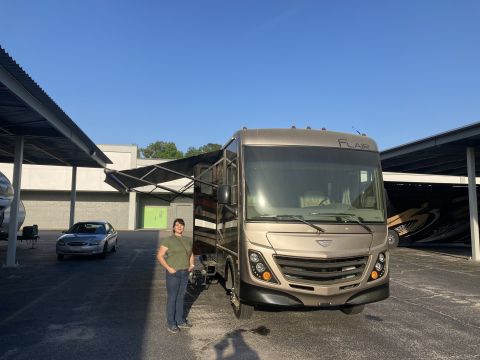 2015 Ford F-550 - A motorhome with an extended awning is parked outside under a covered structure.