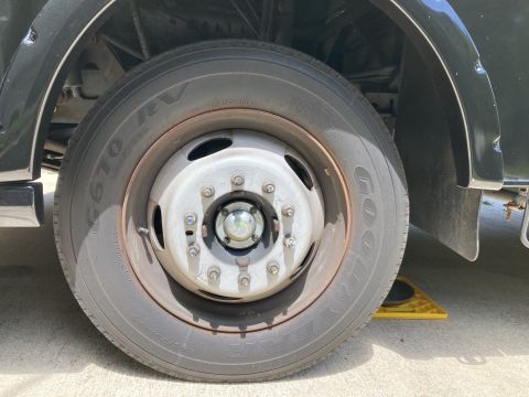 2015 Ford F-550 - Close-up of a heavy-duty truck wheel and tire, with a yellow wheel chock visible underneath.
