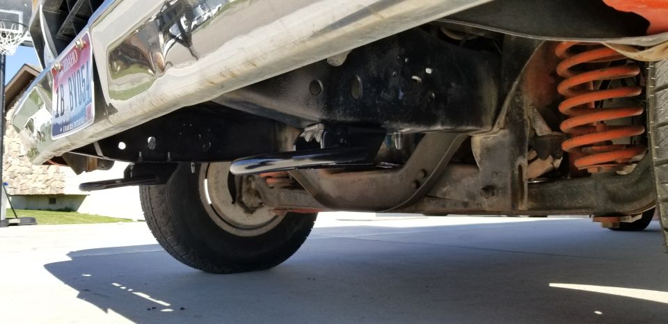 Undercarriage view of a truck showing the frame, suspension, and orange coil springs