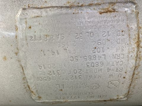 2015 Ford F-550 - Embossed metal certification/ID plate on a vehicle component with raised text, mostly illegible from corrosion.