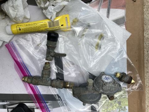 2015 Ford F-550 - A propane regulator and valve assembly, likely for an RV or outdoor grill, is laid out on a surface with cleaning supplies.