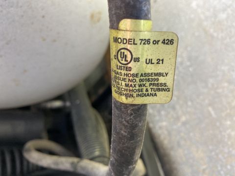 2015 Ford F-550 - A close-up of a propane tank hose assembly, a UL-listed label with model information and manufacturing details from Goshen, Indiana.