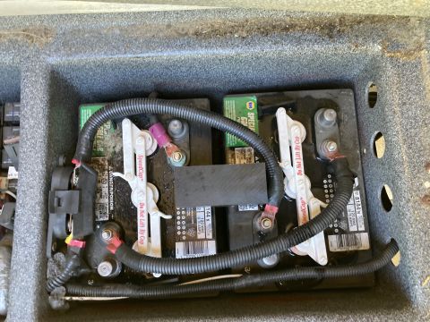 2015 Ford F-550 - Close-up view of house batteries within a compartment, showing wiring and securing mechanisms.