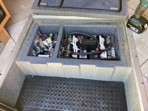 2015 Ford F-550 - Compartment containing house batteries and electrical wiring, with a power tool visible in the background.