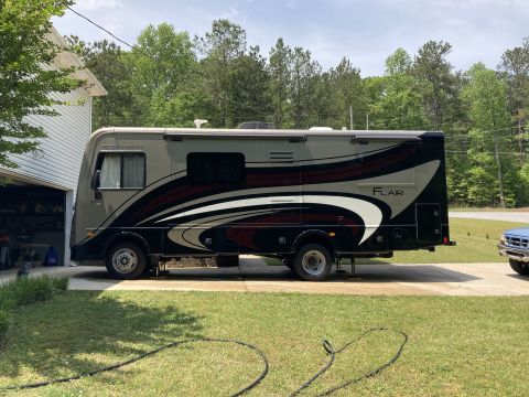 2015 Ford F-550 - Side view of a motorhome with 'FLAIR' graphics parked in a driveway.