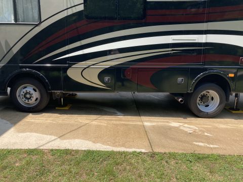 2015 Ford F-550 - Side view of a motorhome with a distinctive graphic paint scheme and visible storage compartments.