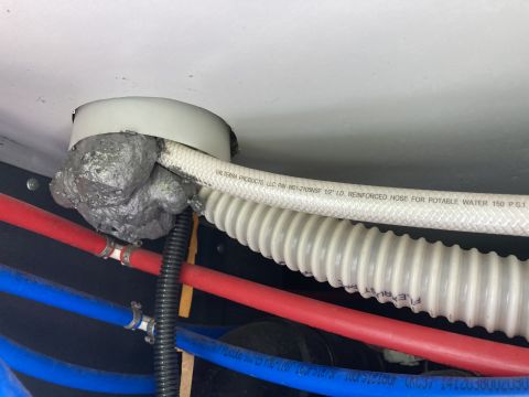 2015 Ford F-550 - Close-up view of plumbing and insulation, with a white hose labeled for potable water.