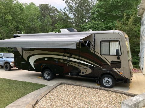 2015 Ford F-550 - Fleetwood Flair RV parked next to a pickup truck with the awning extended.