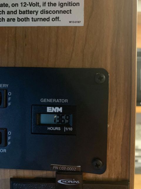 2015 Ford F-550 - A close-up of a generator hour meter and control panel within a wooden cabinet.