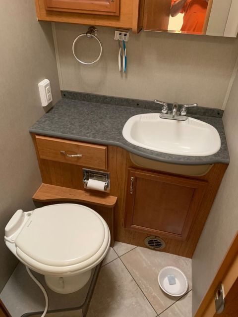 2015 Ford F-550 - Interior view of an RV bathroom a toilet, sink, and storage cabinets.