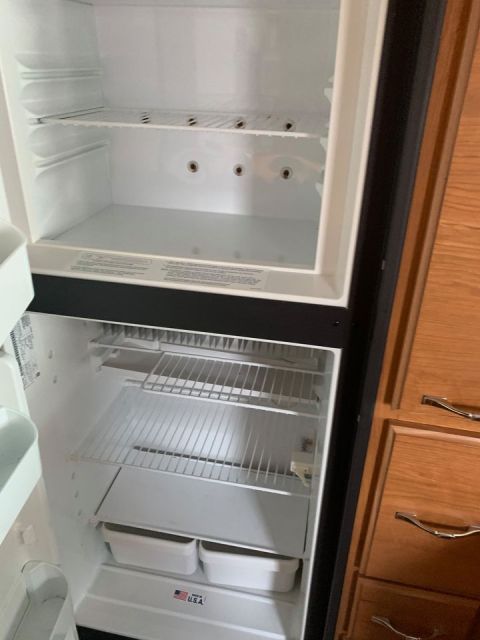 2015 Ford F-550 - The interior of an empty RV refrigerator shows multiple shelves and two drawers at the bottom.