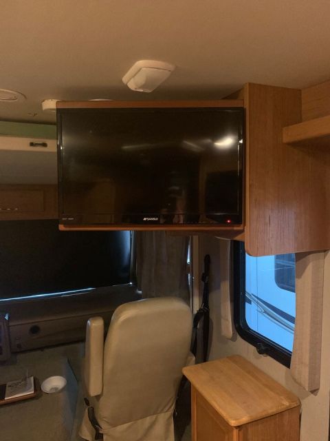 2015 Ford F-550 - Interior view of an RV, showing a TV, seating area, and cabinetry. SuperMotors.net branding is present.