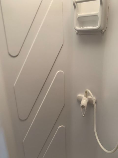 2015 Ford F-550 - Interior view of a shower stall with textured walls and a white shower head.