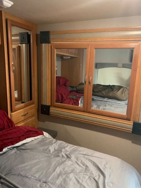 2015 Ford F-550 - Interior view of an RV bedroom a bed, closet, and mirrored cabinets.