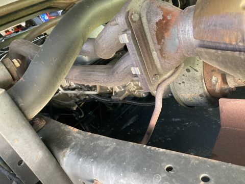 2015 Ford F-550 - Undercarriage shot showing rusted exhaust piping, a mounting bracket and steel crossmembers.
