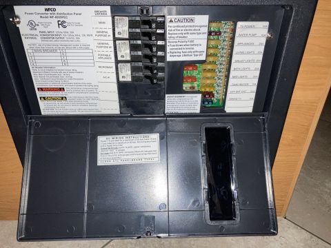 2015 Ford F-550 - Close-up of a WFCO WF-8955PEC power converter and breaker box, showing AC breakers and DC fuses.