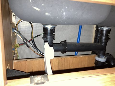 2015 Ford F-550 - The plumbing and wiring beneath an RV sink are visible, with black pipes and various colored wires.
