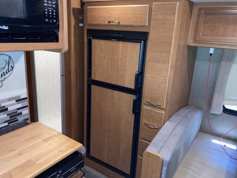 2015 Ford F-550 - Interior view of an RV, highlighting the kitchen and seating area with wood cabinetry.