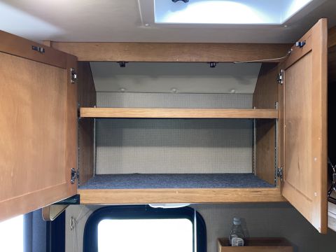 2015 Ford F-550 - Interior view of open overhead storage cabinets with wooden doors and shelves.
