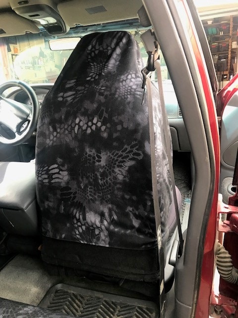 2000 Ford Explorer - Front seat fitted with a black Kryptek-pattern camo seat cover inside a red truck cab.