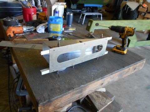1992 Ford Bronco - A metal bracket with two oval cutouts sits on a workbench, with tools and supplies in the background.