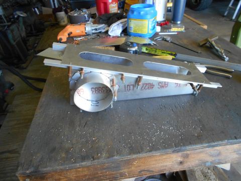1992 Ford Bronco - Metal part with visible text and markings sits on a workbench with various tools in the background.