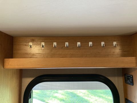 2015 Ford F-550 - A row of eight small, silver hooks are mounted on a wooden panel above a shelf. The hooks are evenly spaced and appear to be for hanging it…