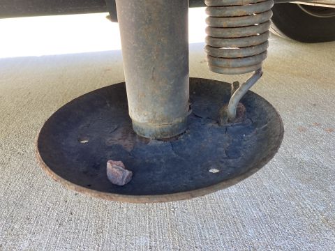 2015 Ford F-550 - A close-up view of the base of a trailer jack with a large spring attached. The metal base plate is round and shows significant rust and we…