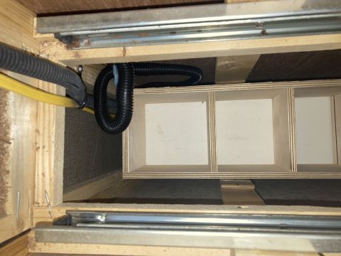 2015 Ford F-550 - A close-up view shows the interior of a wooden compartment with black corrugated tubing and a yellow wire running through it. The compartme…