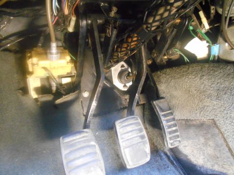 1992 Ford Bronco - This is a close-up view of the driver's side footwell in a vehicle, showing the clutch, brake, and accelerator pedals. A yellow hydraulic c…