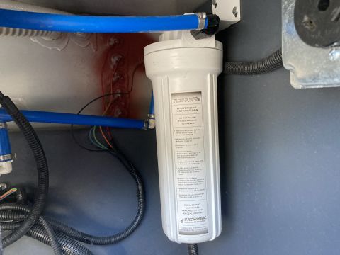 2015 Ford F-550 - A white water filter housing with winterizing instructions is visible, connected to blue plumbing lines. Electrical wires and black corruga…