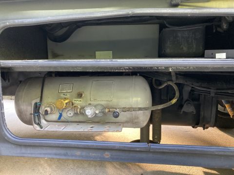 2015 Ford F-550 - A propane tank with fill and vapor valves is visible in an open storage compartment of an RV.
