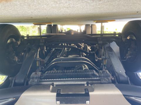 2015 Ford F-550 - Underside view of a large truck chassis, showing the front suspension, radiator, and tires. The vehicle appears to be elevated, with yellow…