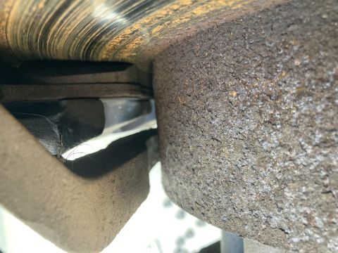 2015 Ford F-550 - A close-up view of a heavily rusted brake rotor and caliper assembly on a vehicle. The brake pad appears worn, with a thin layer of materia…