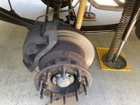 2015 Ford F-550 - A close-up, low-angle view of the front driver's side brake assembly of a heavy-duty truck, showing the brake caliper, rotor, and hub with…